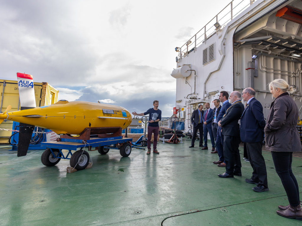 A group of invited guests gather around Boaty McBoatFace and learn about the important role autonomous underwater vehicles play in ocean research