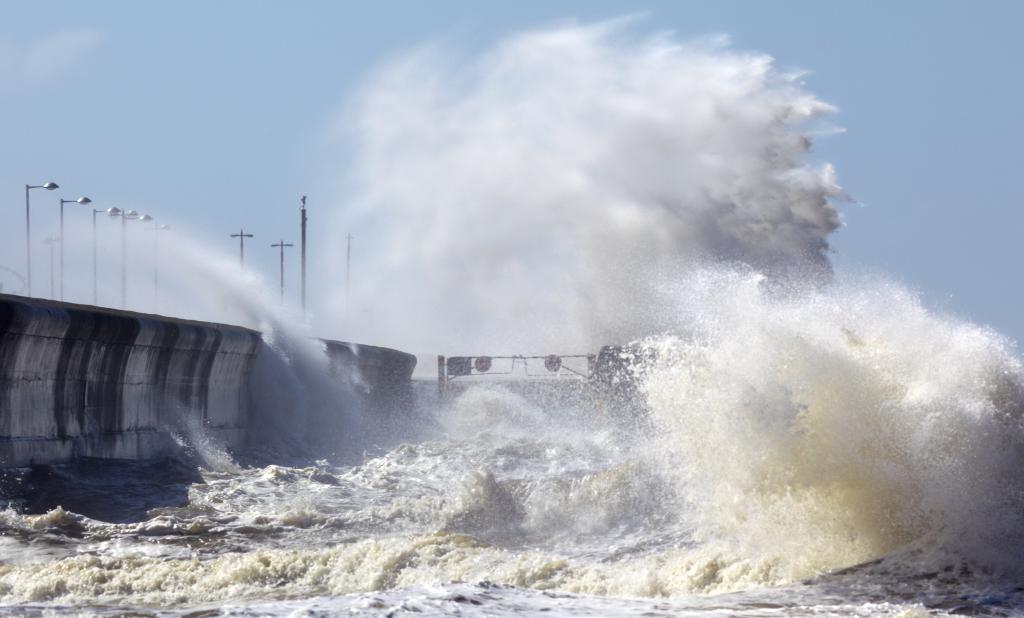 A large wave crashes against the shore