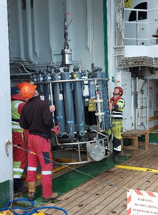 The ship's crew prepare to deploy a scientific instrument from a research vessel