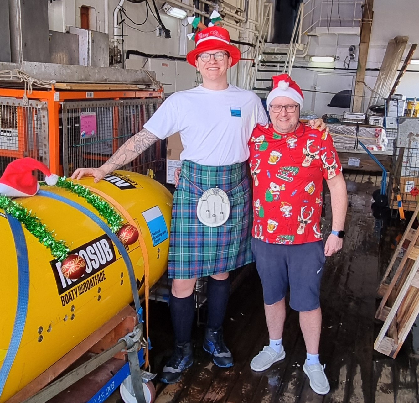 RRS James Cook Captain John Leask (right) and electro technical officer Harvey Jack (left) with the NOC’s Autosub Long Range (ALR) underwater robot (aka Boaty McBoatface), complete with some festive tinsel. 