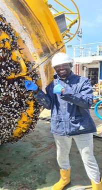 Scientist inspecting barnacles under a large ocean buoy